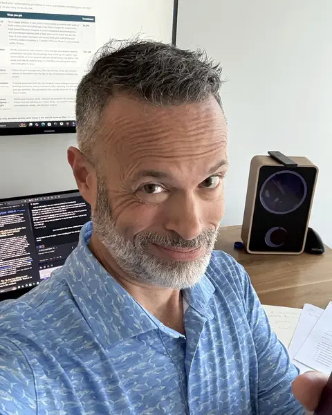 Adam LaBare at his desk, smiling, two screens behind him